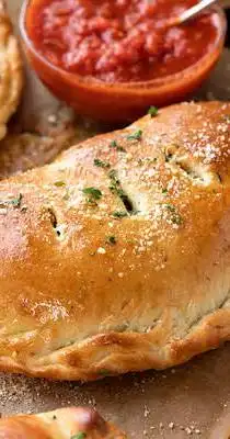 Golden-brown calzone with marinara sauce